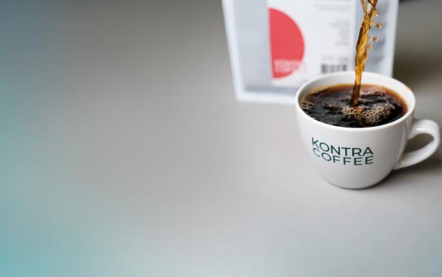 stribe af tre kaffekrus staar paa et bord i baggrunden mennesker ses i baggrunden