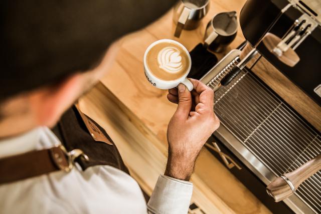 barista har brygget en kop kaffe med latterat i toppen