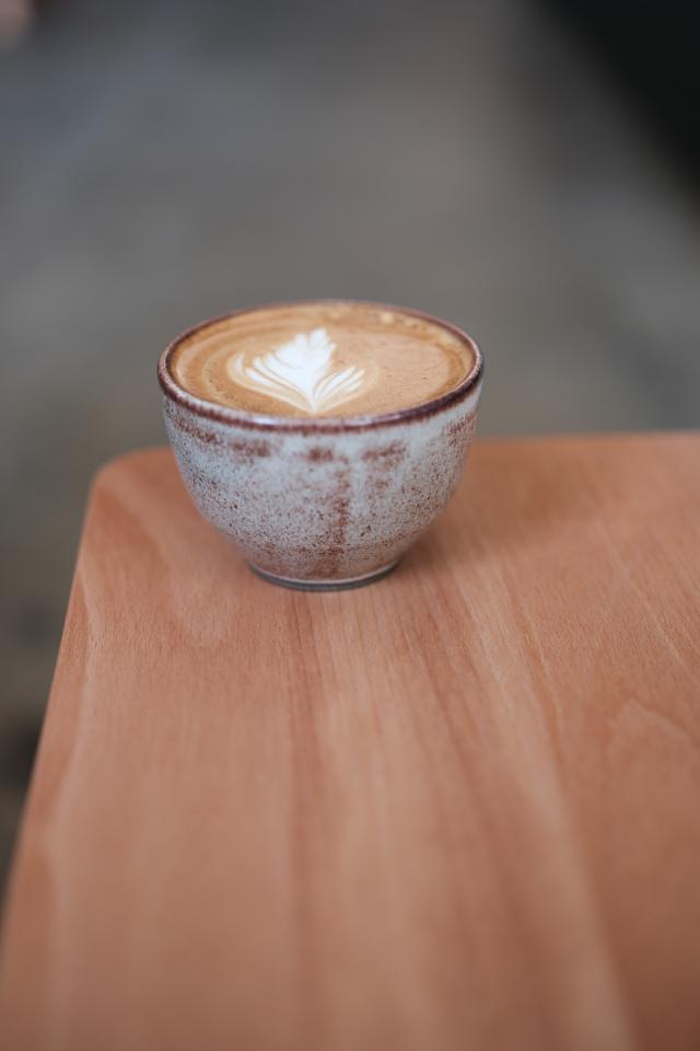 cappuccino med latteart i keramikkop staar paa et bord