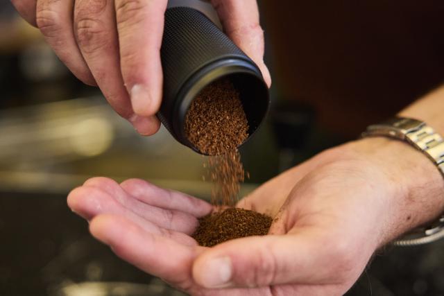 person haelder formalet kaffe fra en lille beholder ned i sin haand