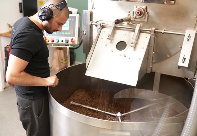 ristemester kigger på kaffeboenner der er ved at blive ristet
