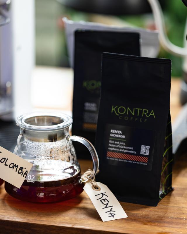 glaskande med kenya kaffe staar foran en kaffepose med kenya kaffeboenner